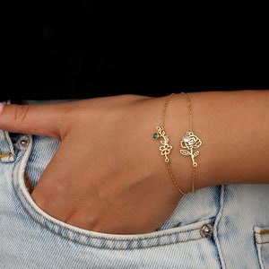 Silver-tone charm bracelet with a green flower pendant and small dangling detail