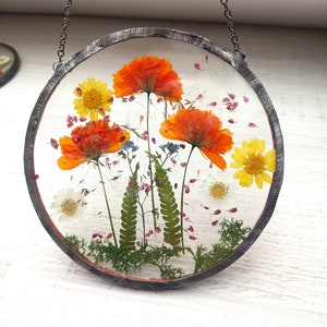 Hanging floral stained-glass suncatcher with orange and yellow dried flowers in a round frame