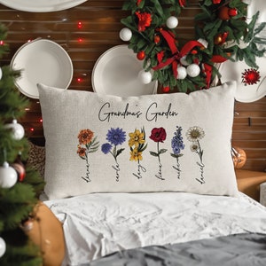 Cream throw pillow with embroidered garden flowers and cursive Grandma text