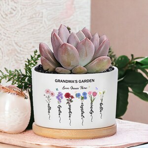 White ceramic plant pot with printed flowers and text, holding a pink succulent