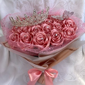 Pink rose bouquet with rhinestone tiara topper, tulle wrap, and satin bow ribbon