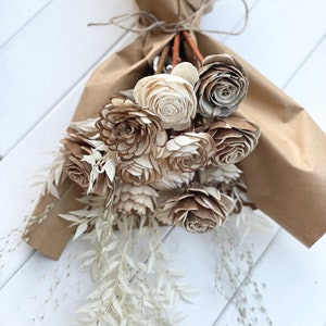 Sola wood flower bouquet with beige and brown blossoms and white filler, wrapped in kraft paper