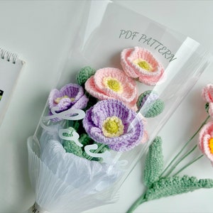 Crochet flower bouquet with pastel pink and purple blooms and green leaves in a bag
