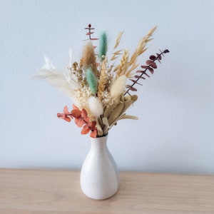 Mini dried floral bouquet in white vase with burnt orange and white dried flowers