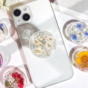 Transparent folding phone holder grip with pressed dried blue flowers in a circle