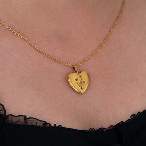 Gold heart-shaped locket necklace with floral engraving on a small pendant