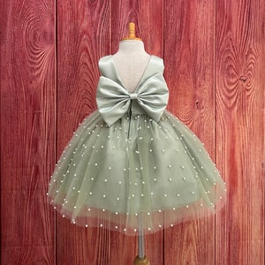 Sage green tulle knee-length dress with large back bow and pearl-like dotted overlay