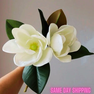 Lifelike magnolia bouquet with white flowers and green leaves, held in hand