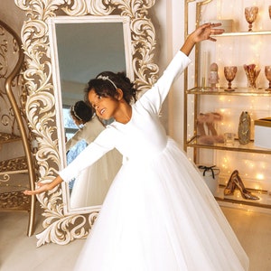 White long-sleeve tulle flower girl dress with bow and full skirt, back view