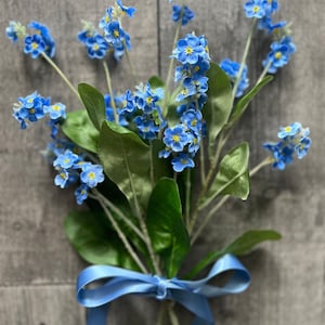 Silk forget-me-not flower bunch with blue blooms, green leaves, and matching blue ribbon