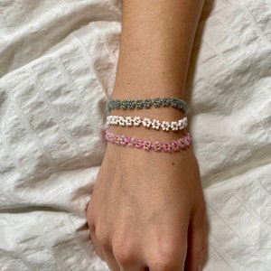 Beaded flower bracelet with gold center, worn on wrist; pink and light blue bead bands