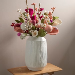 Handmade felt flower bouquet with mixed pink, peach, and cream blooms in white vase