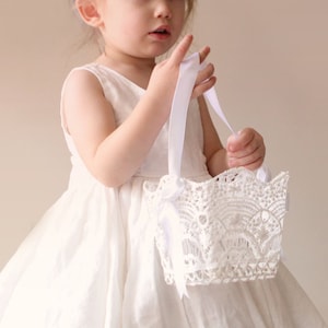 White stiffened crochet lace flower girl basket with short handles and floral pattern