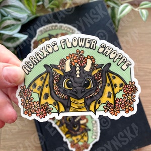 Clear vinyl sticker with black dragon, yellow wings, and floral circular border