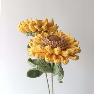 Handmade knitted sunflower with brown center and green leaves on stems