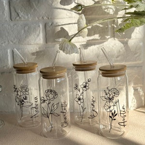Custom 16oz glass iced coffee cups with lids, straws, and etched birth-flower designs