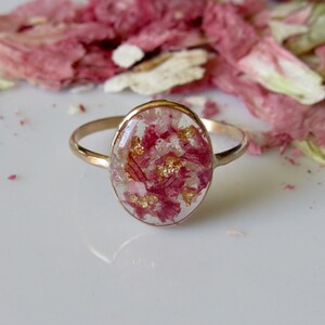 Gold-filled oval flower preservation ring with pink pressed petals in clear oval bezel