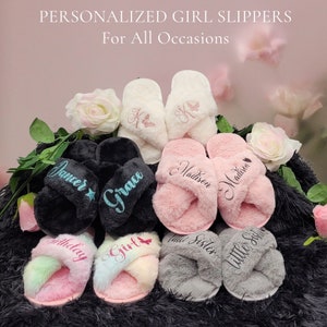 Assorted plush kids slippers in pink, black and gray with embroidered names and flower details