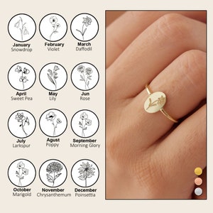 Sterling silver birth flower ring with small bloom charm, worn on finger.