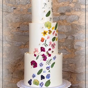 Cake decorated with pressed mixed edible flowers, pink, purple, blue and green accents