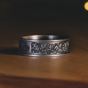 Silver band ring with engraved floral and leaf pattern across the front