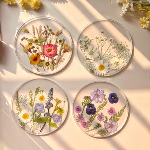 Set of round coasters with colorful pressed wildflowers in clear glass, four designs