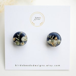 Round floral resin stud earrings with pressed flowers and gold flecks, dark blue backing