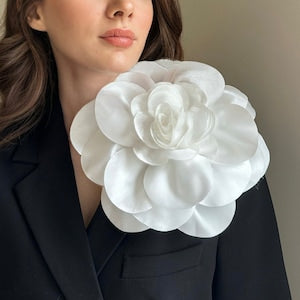 Oversized white flower brooch with layered rose petals, pinned on blazer lapel