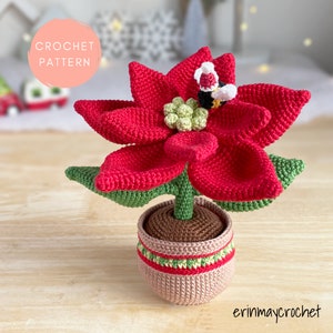 Crochet poinsettia flower with red petals and green center in small fabric pot