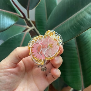 Baby foot badge reel with gold-tone round charm and pink enamel accents