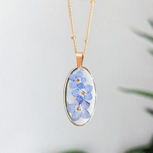 Gold-plated necklace with oval pendant and blue forget-me-not flowers