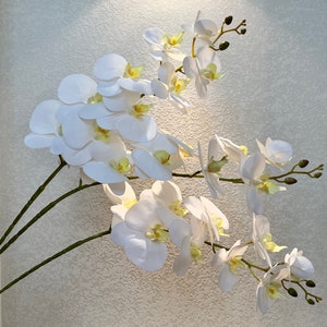 Artificial white orchid flower stem with multiple blooms and yellow centers