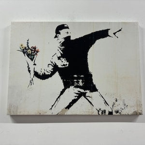 Banksy street art print of stenciled figure tossing flowers on off-white canvas