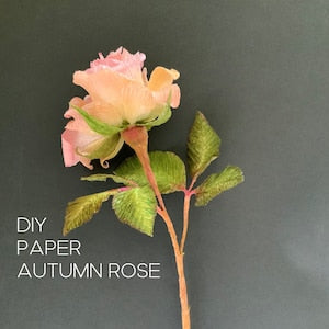 Crepe paper autumn rose with pink layered petals and green leaves on a stem