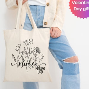 Canvas nurse tote bag with wildflower and nurse text graphic, wide shoulder handles