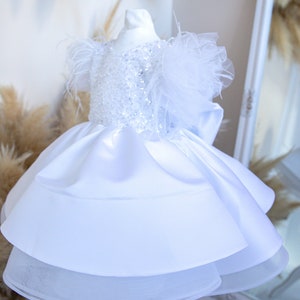 White sequin satin baby dress with tulle feather sleeves and layered skirt