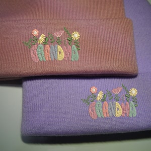 Floral grandma embroidered beanie, folded; mauve and lavender knit hats with flower motif