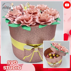 Round gift box with pink paper flower rosettes and green ribbon, top open with chocolates