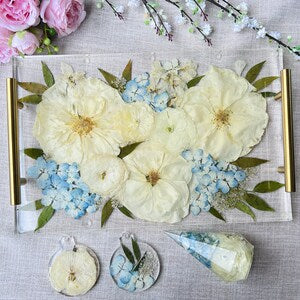 Preserved wedding bouquet floral arrangement on gold tray with white and light blue blooms