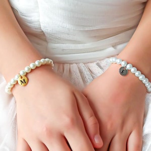 White pearl flower girl bracelet on hands, with small letter charms