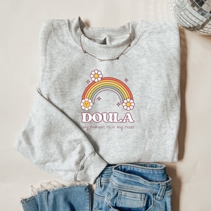 Light gray crewneck sweatshirt with rainbow DOULA graphic and small slogan