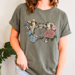 Sage green graphic tee with pelvic anatomy and floral rose print