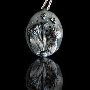 Fine silver oval pendant necklace with raised wildflower and leaf design
