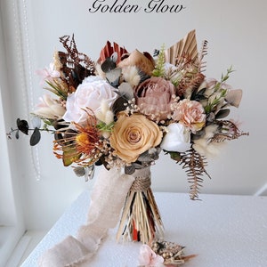 Boho bridal bouquet with peach, pink, and tan flowers, dried grasses, and ribbon ties