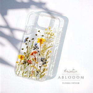 Clear pressed-flower phone case with yellow and orange wildflowers under glass