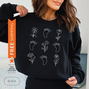 Black crewneck sweatshirt with white wildflower and paw-print graphic