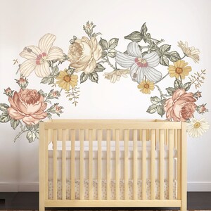Watercolor floral wall decal with oversized blooms above a crib
