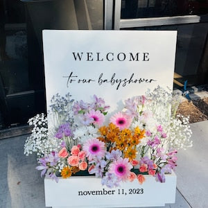 Wedding welcome sign with floral box; “WELCOME” and “November 11, 2023” on white board