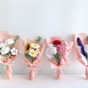Crochet flower bouquet with assorted blossoms, wrapped in pink paper and ribbon bows