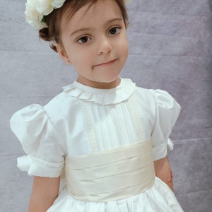 Ivory flower girl dress with puff sleeves, ruffled collar, and pleated bodice